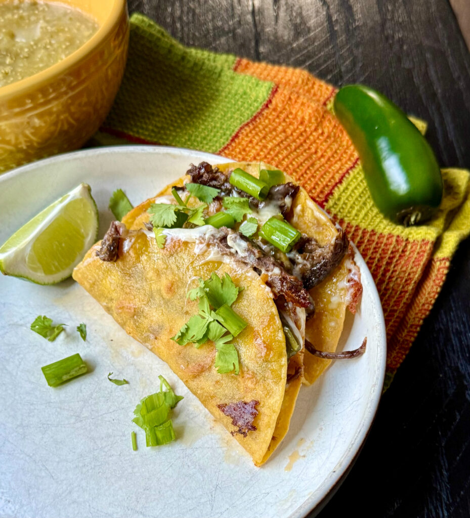 Slow cooked mole pot roast tacos topped with fresh salsa verde and served on warm corn tortillas