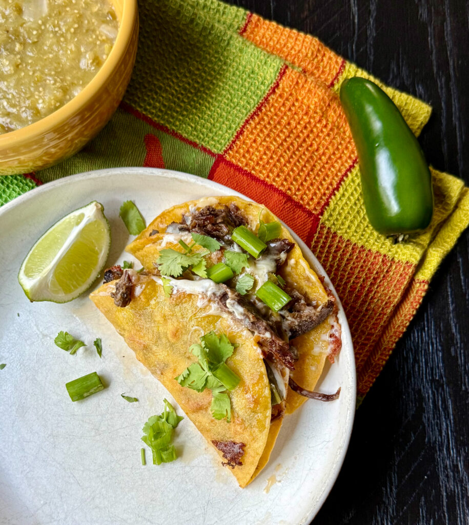 Slow cooked mole pot roast tacos topped with fresh salsa verde and served on warm corn tortillas