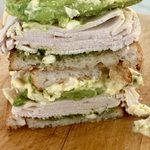 Leftover turkey pesto melt on sourdough, cut and stacked, with avocado and banana peppers