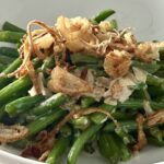Healthier gluten-free green bean casserole topped with crispy fried shallots in a white bowl