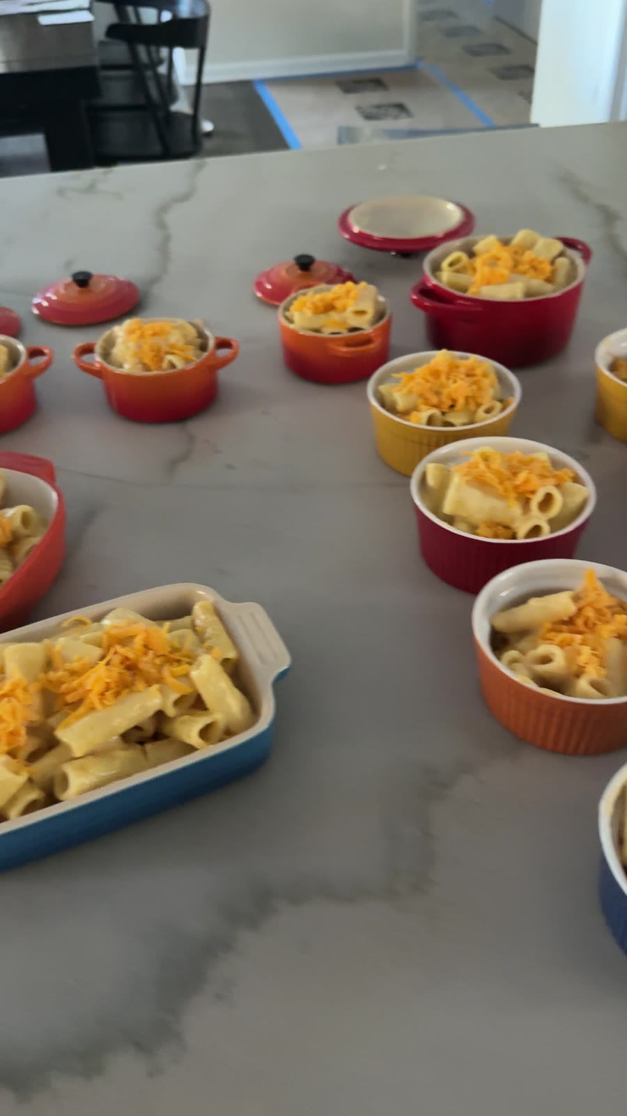 Four batches of mac and cheese topped with cheddar, ready to bake