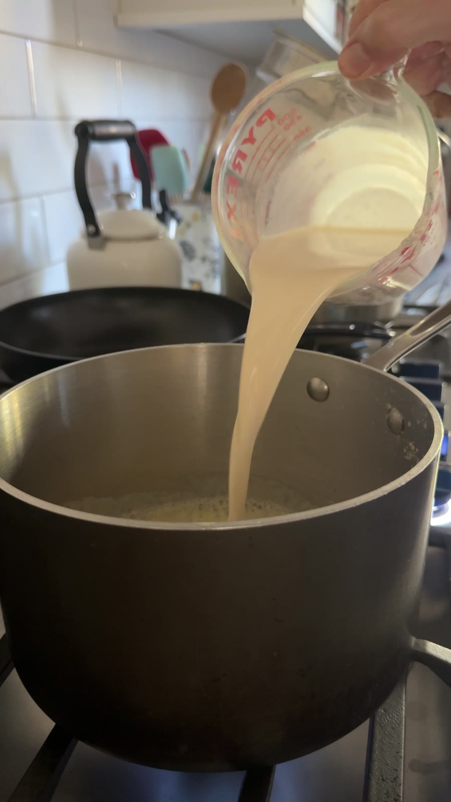 Pouring evaporated milk into the roux for mac and cheese