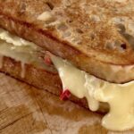 Turkey and brie melt on sourdough with melted brie and mozzarella oozing out the side