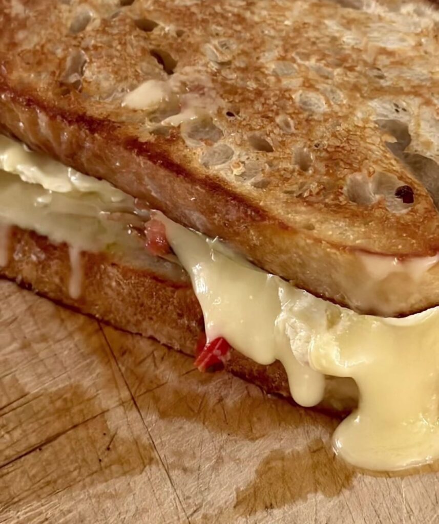 Turkey and brie melt on sourdough with melted brie and mozzarella oozing out the side