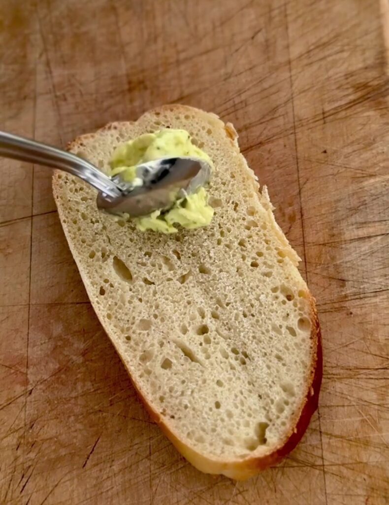 Spreading basil mayo on a sliced sourdough sub roll