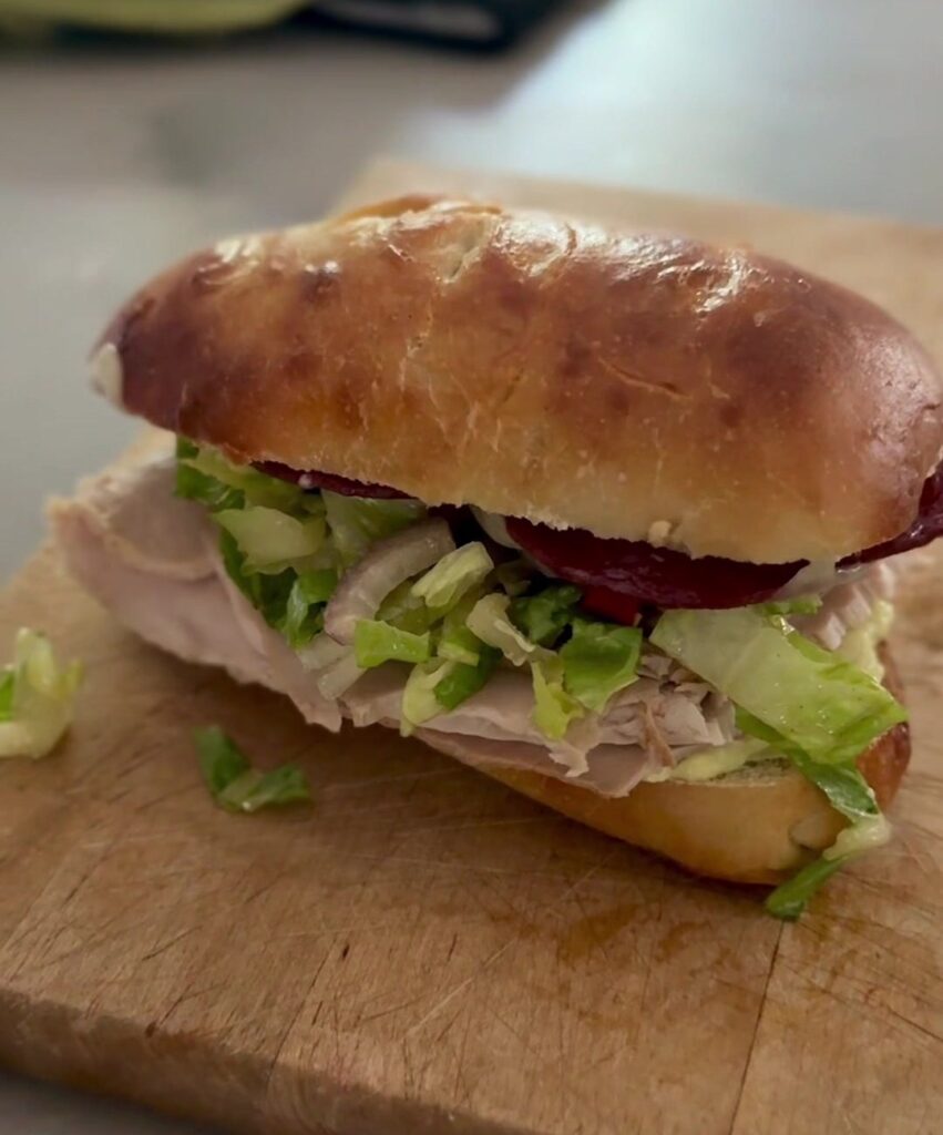 Turkey sub on a homemade sourdough roll with chopped salad, salami and melted cheese